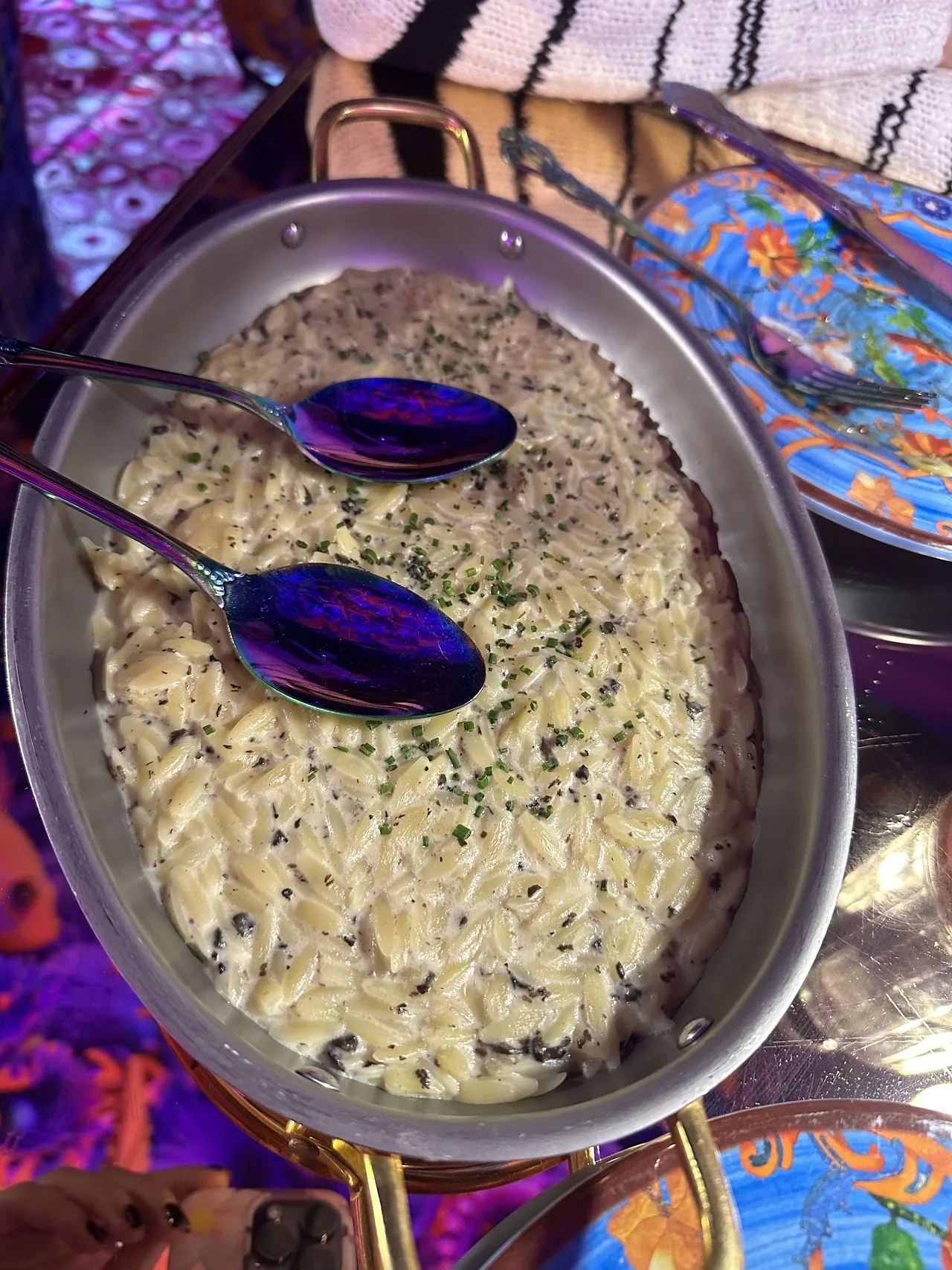 A creamy rice dish served in a metal pan with two spoons