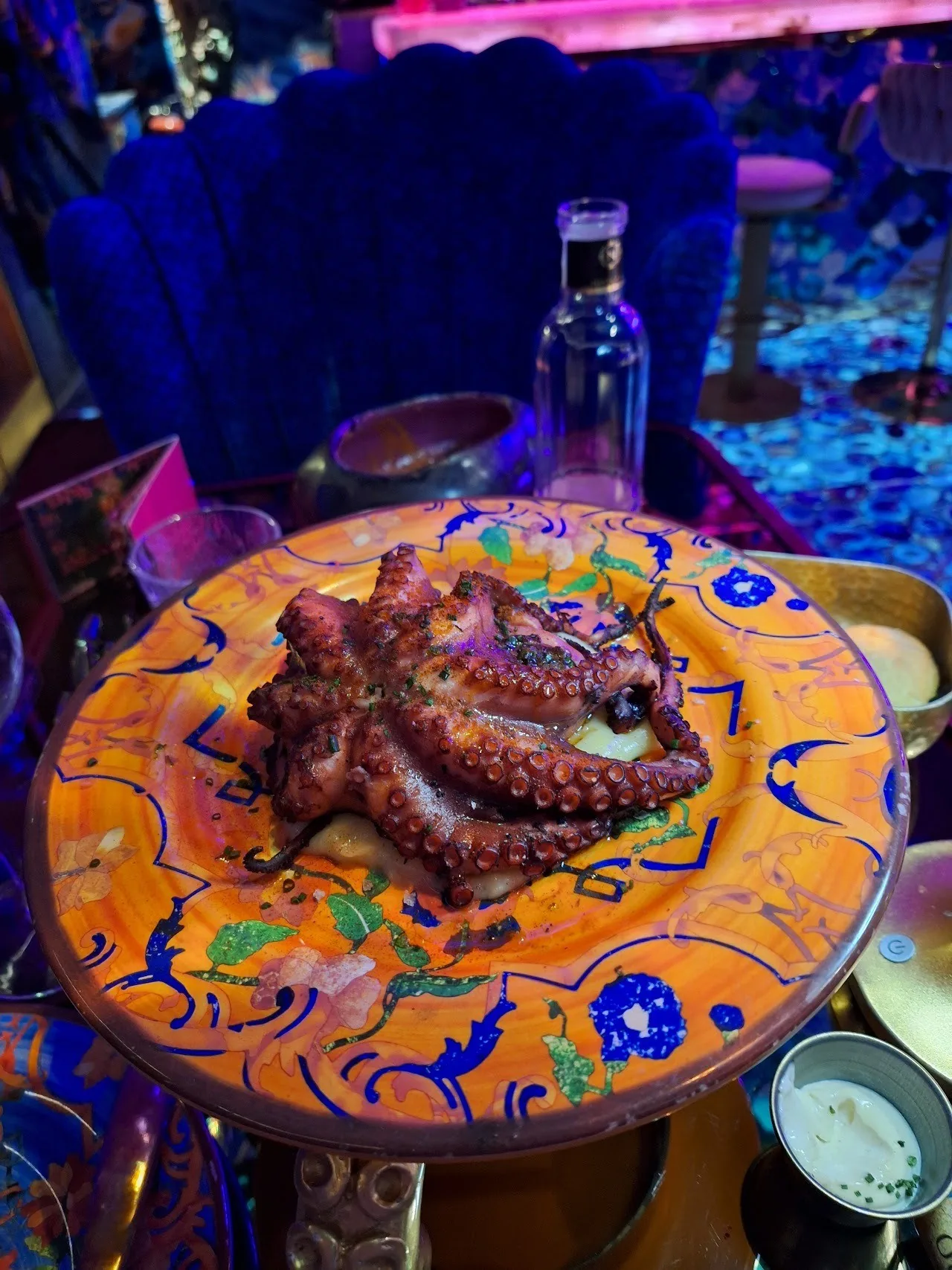 A whole cooked octopus on a colourful patterned plate