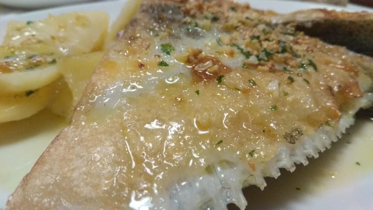 A fish fillet in a buttery sauce with lemon