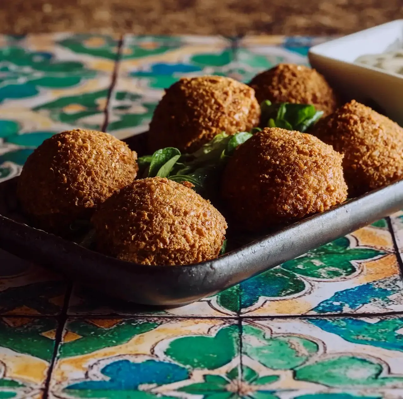 A close view of golden fried falafel balls on a dark serving dish