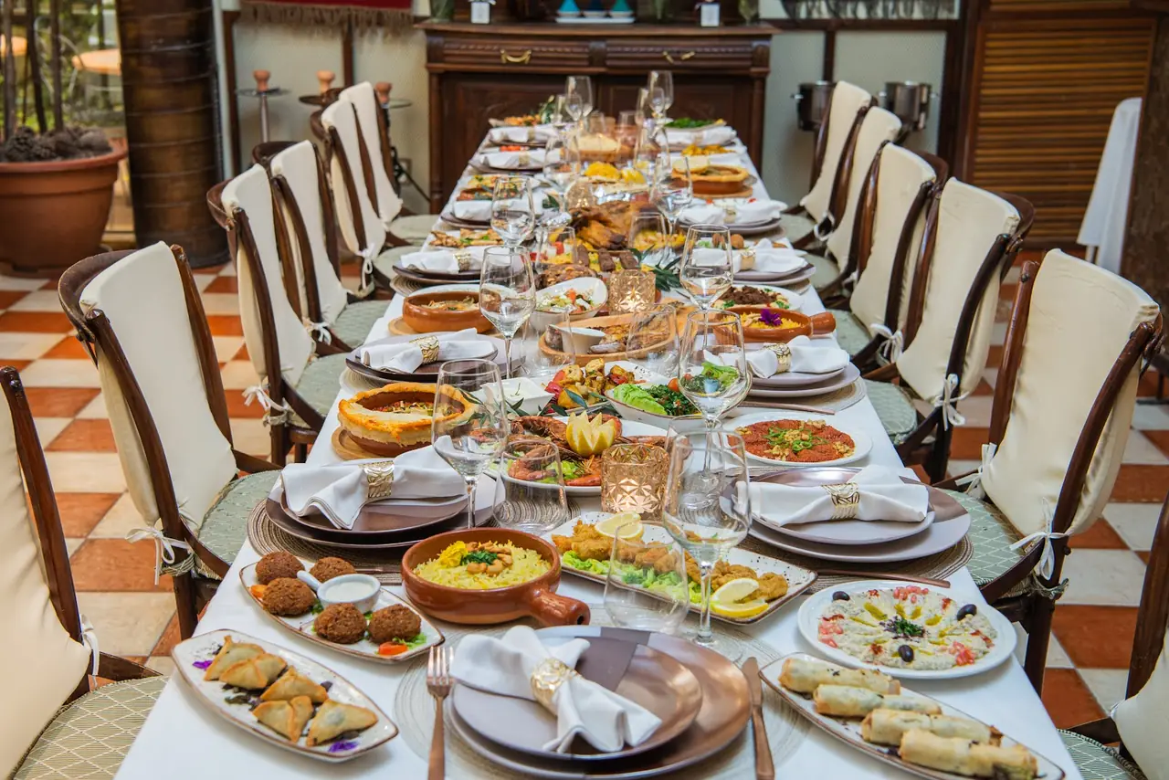 Long table set with a full Middle Eastern spread including falafel, samosas, hummus, rice, seafood and spring rolls