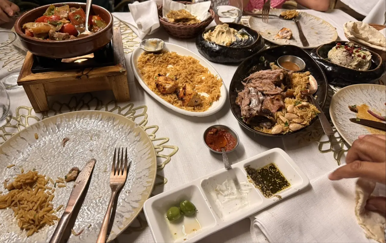 Table spread with tagine, rice with grilled chicken, lamb with rice, hummus and dips