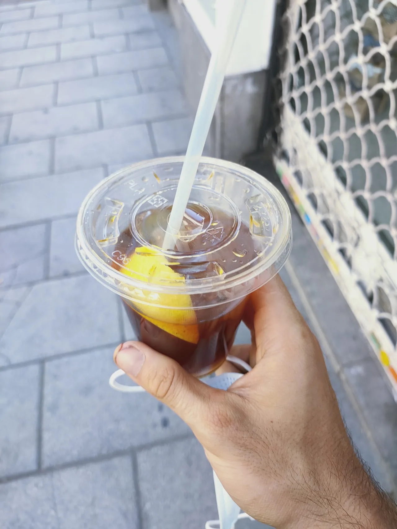 An iced coffee in a plastic cup held in hand