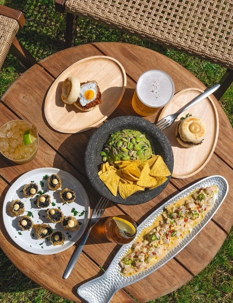 A round wooden table with plates of food and drinks seen from above