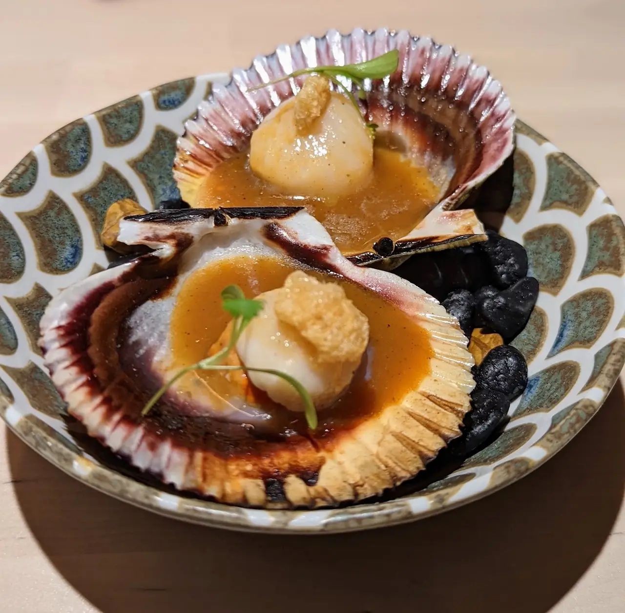 Two scallops served in their shells with a caramel-colored sauce.
