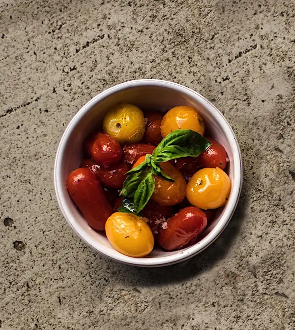 A bowl of mixed red and yellow cherry tomatoes topped with fresh basil leaves, Bistrot Levante
