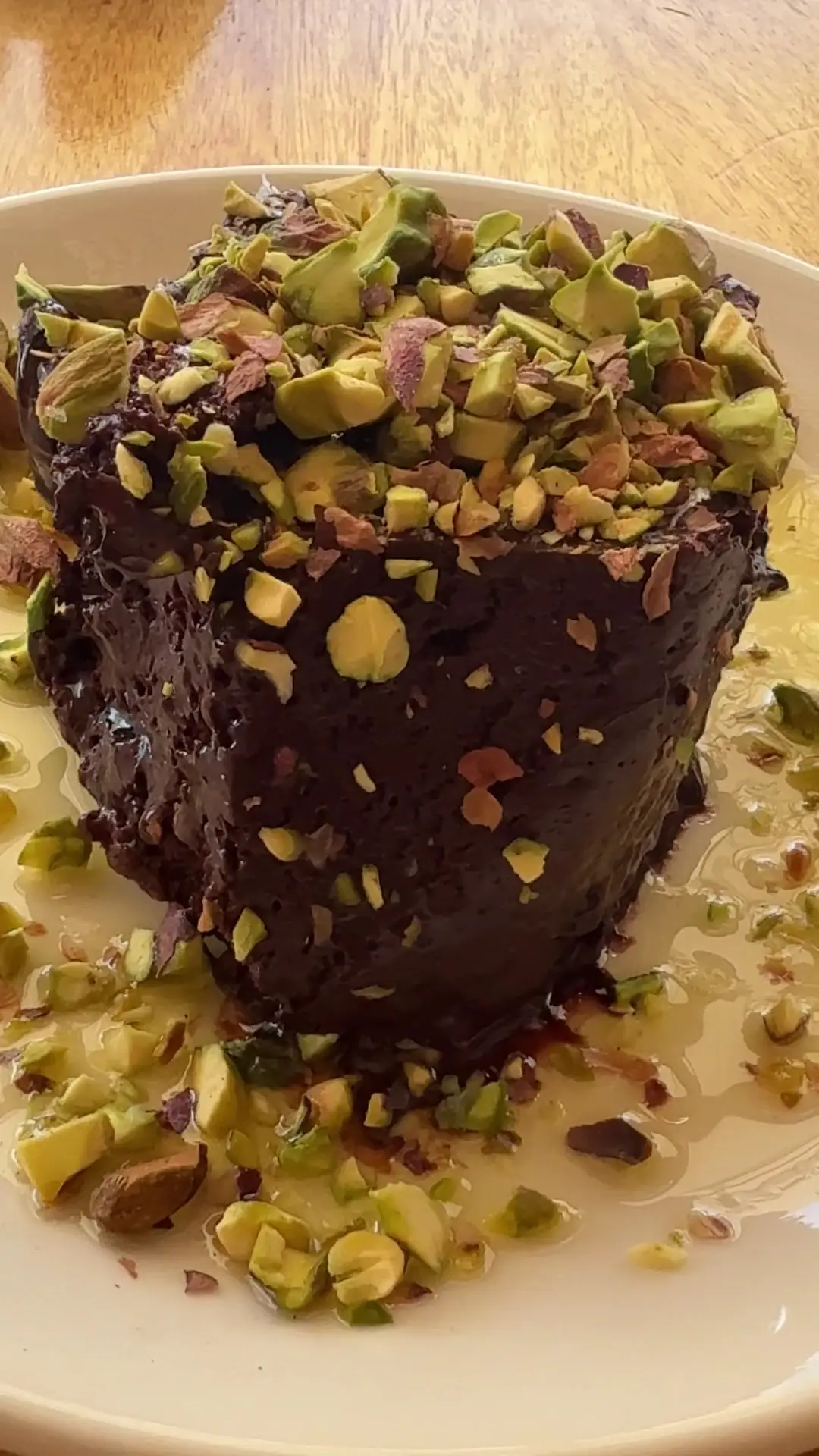 A slice of chocolate cake topped with crushed pistachios.