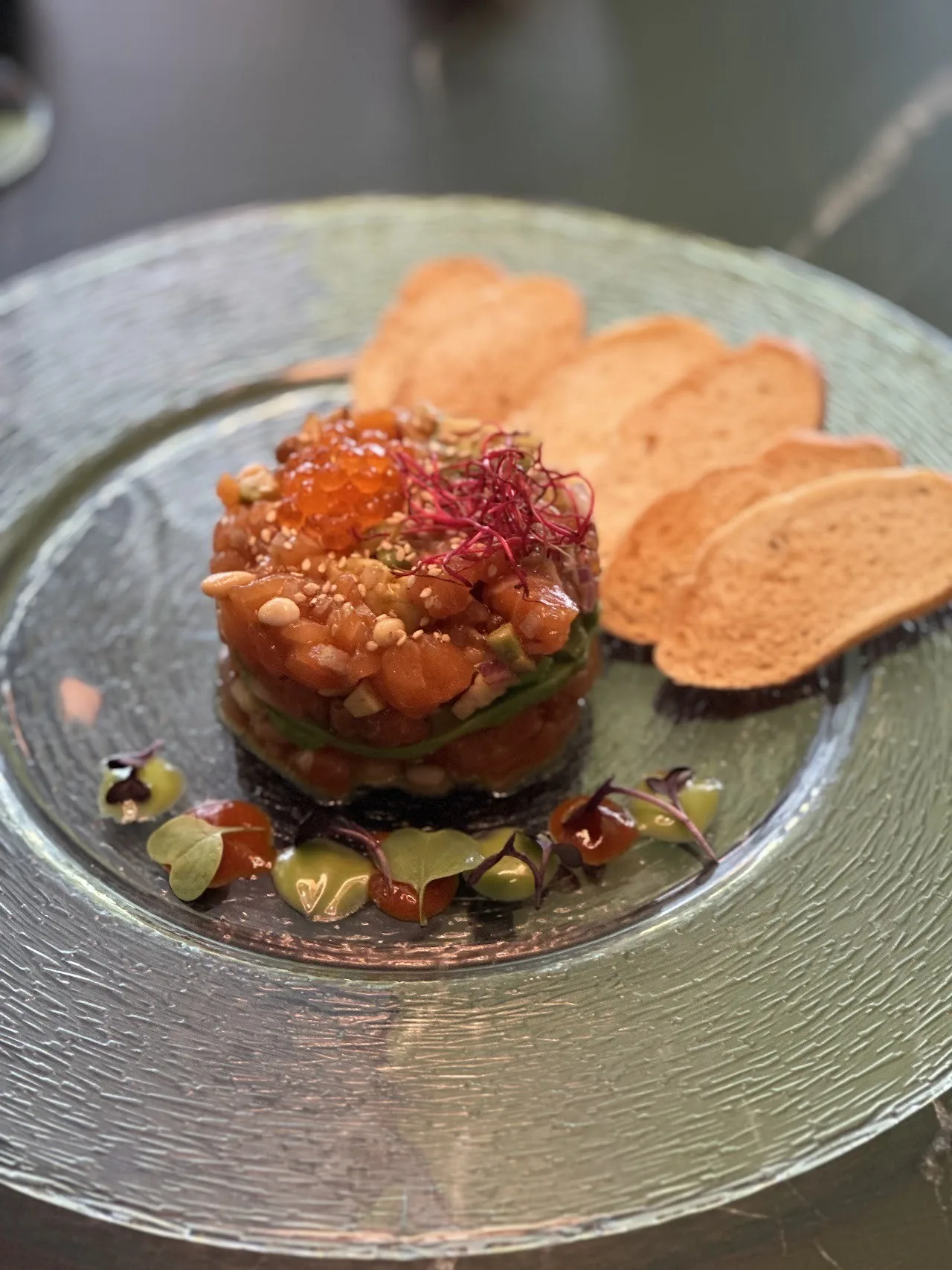 A stacked tartare with crisps on a glass plate