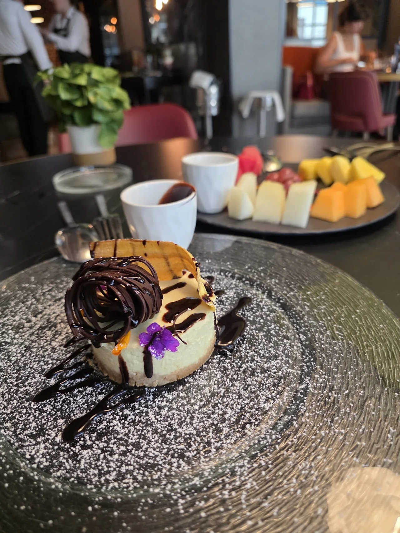 A dessert with chocolate drizzle, meringue, and fruit garnish on a dark plate