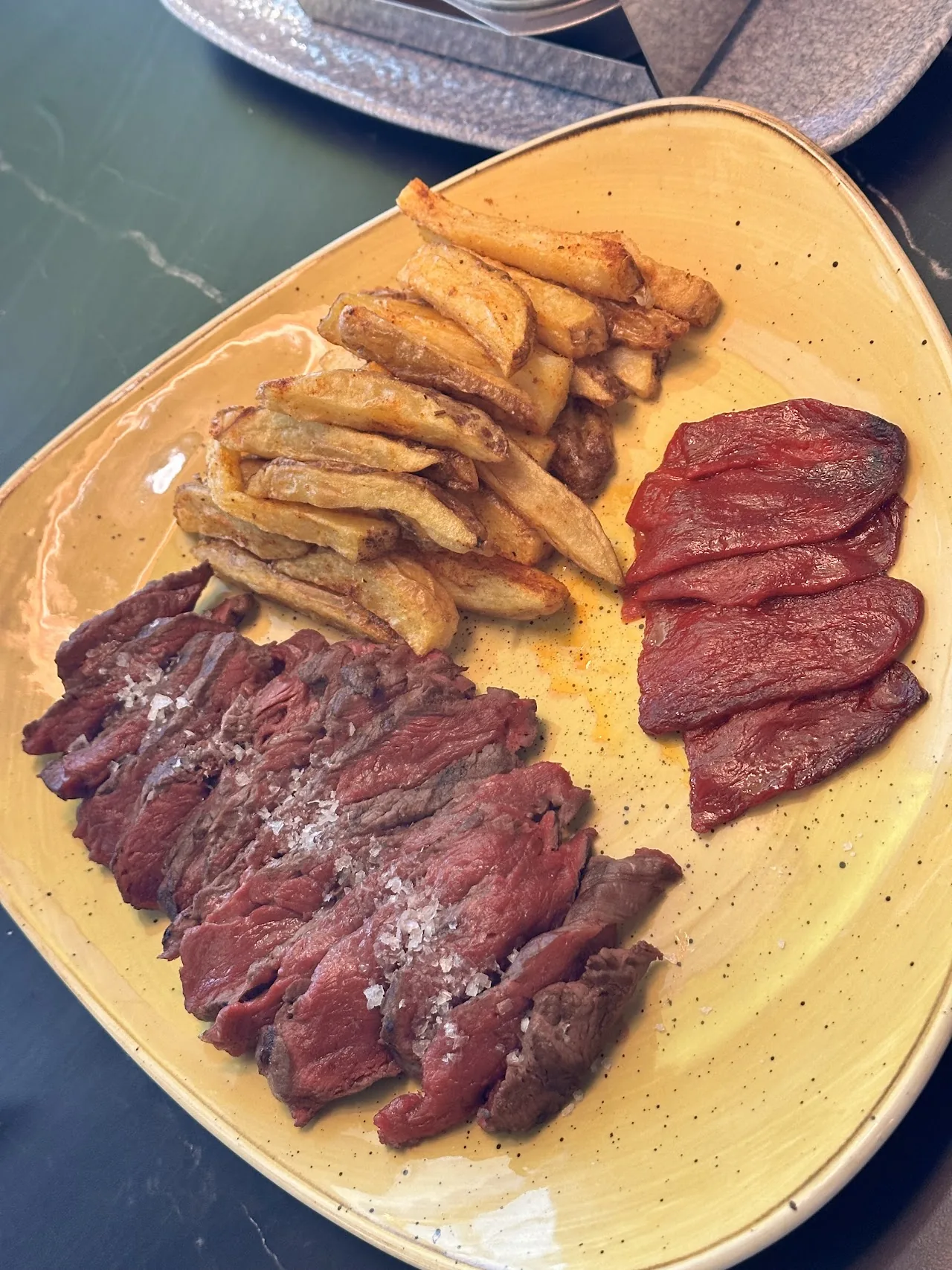 Sliced medium-rare meat with roasted potato wedges on a plate