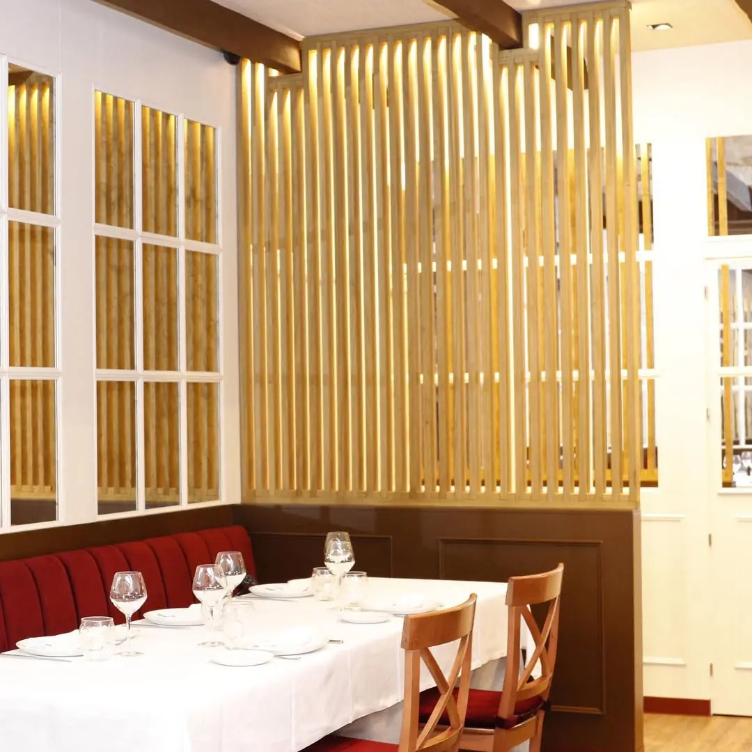 Booth dining table set with wine glasses and white tablecloth beside a slatted wood partition