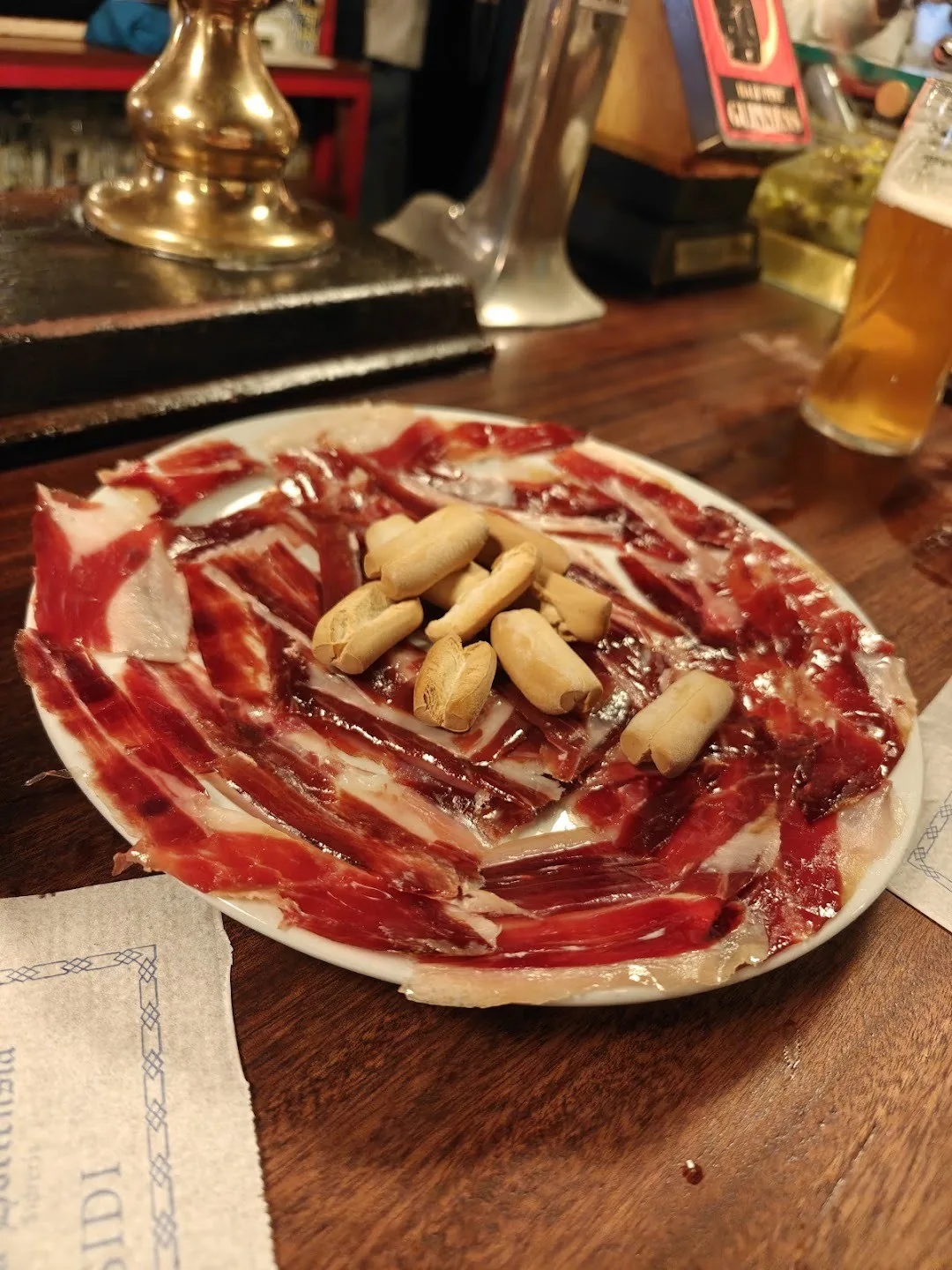 A plate of sliced cured ham with a few nuts on top
