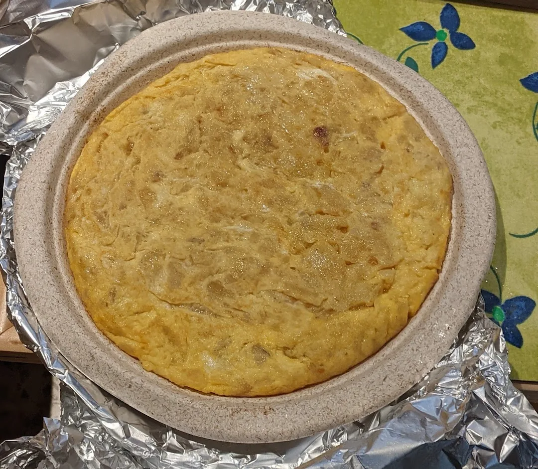 A whole golden tortilla espanola on a round plate, seen from above