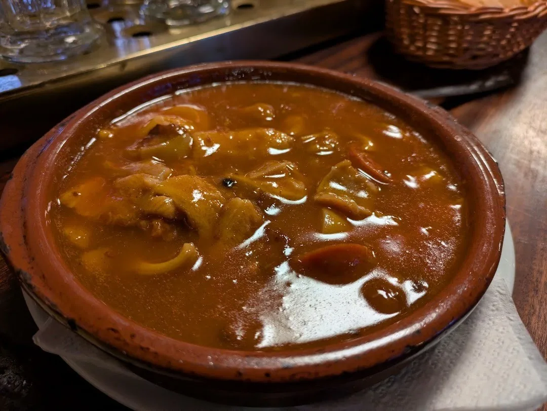 A brown earthenware bowl of stew on a bar counter
