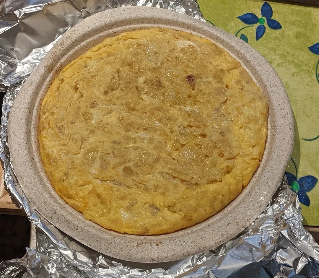 A whole Spanish omelette on a plate lined with foil