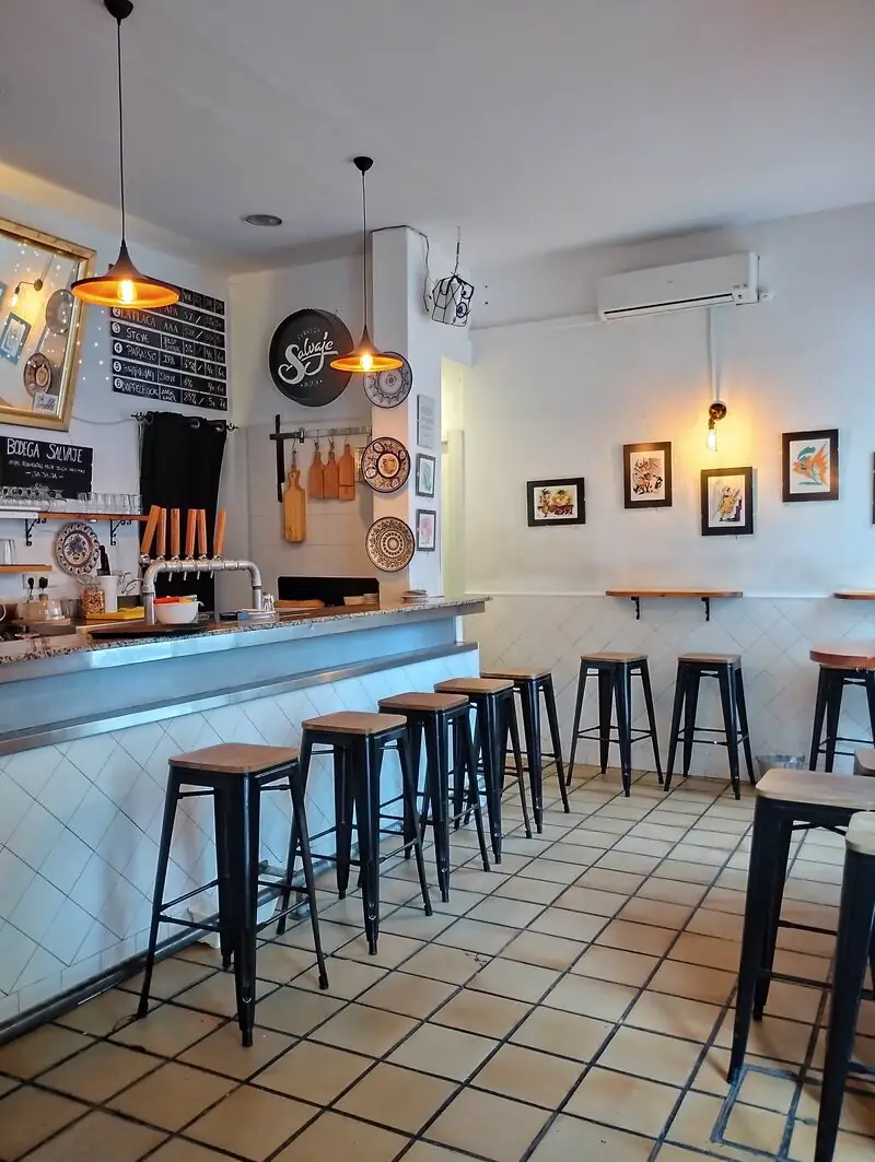 Bodega Salvaje bar interior in portrait, beer taps and Salvaje branding on the wall, black stools lined along a tiled granite counter