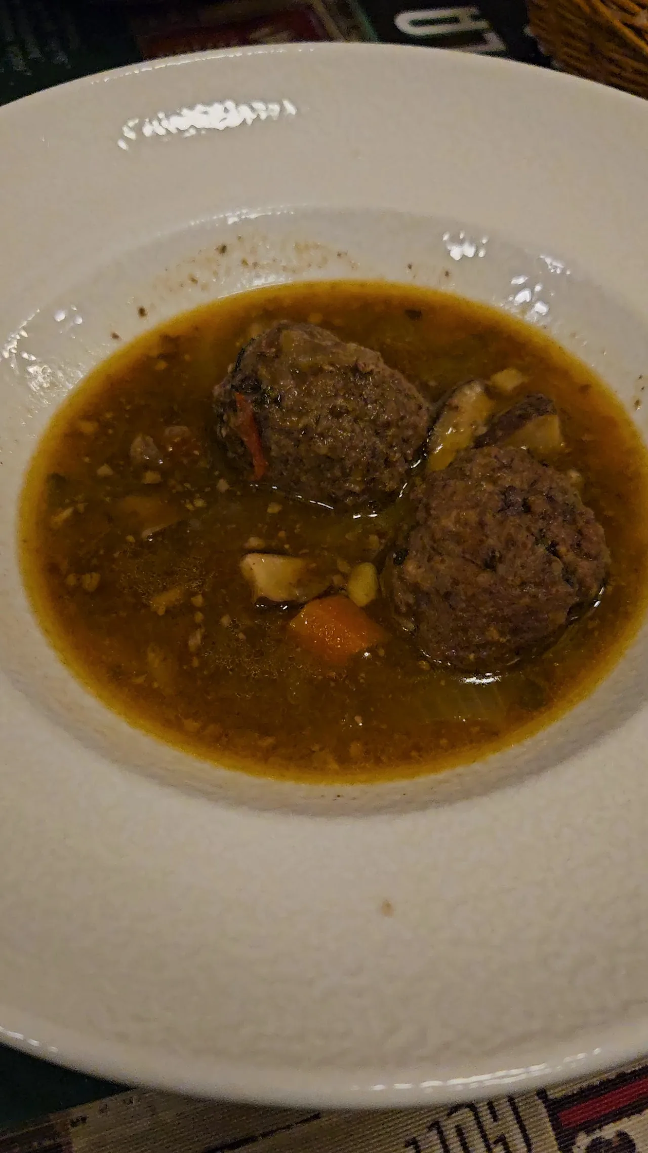 A bowl of soup with meatballs, chickpeas, and carrots