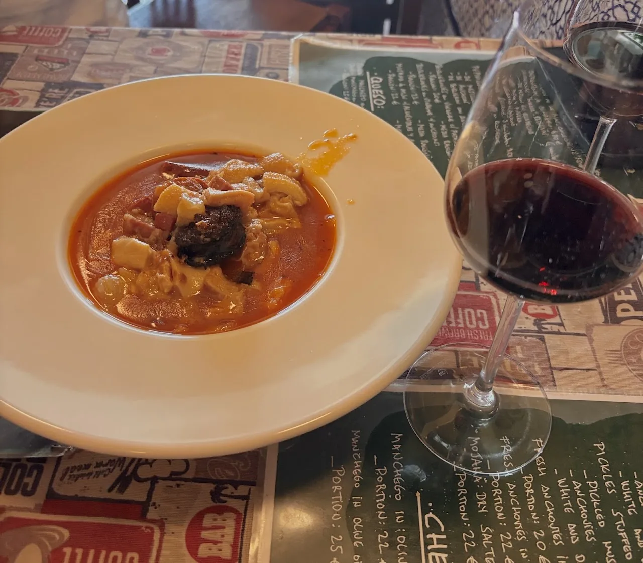 A plate of stew in tomato sauce paired with a glass of red wine