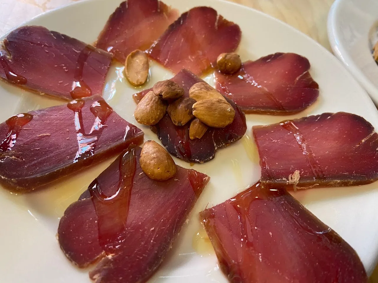 Thin slices of cured meat garnished with almonds