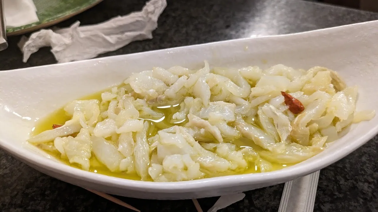 A white dish of shredded salted cod dressed in olive oil