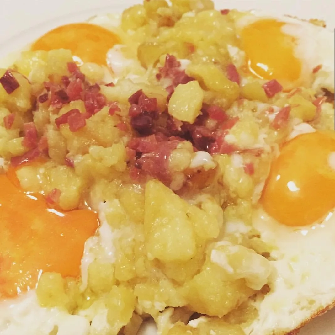 Fried eggs with diced ham broken over potatoes