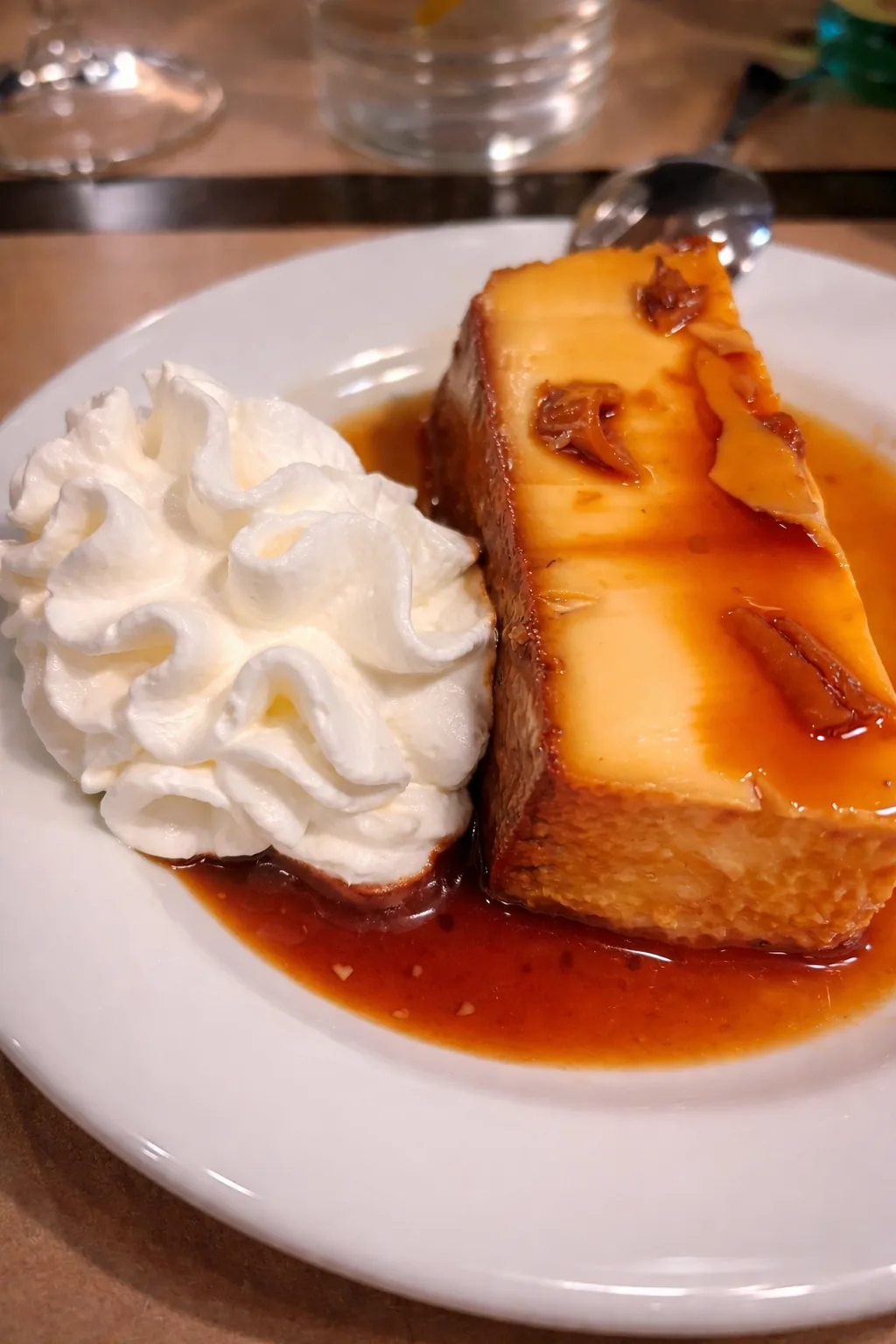 A slice of flan dessert topped with caramel sauce and whipped cream