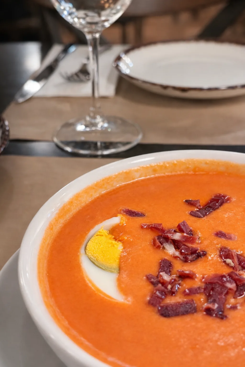 A bowl of gazpacho garnished with chopped egg and jamon