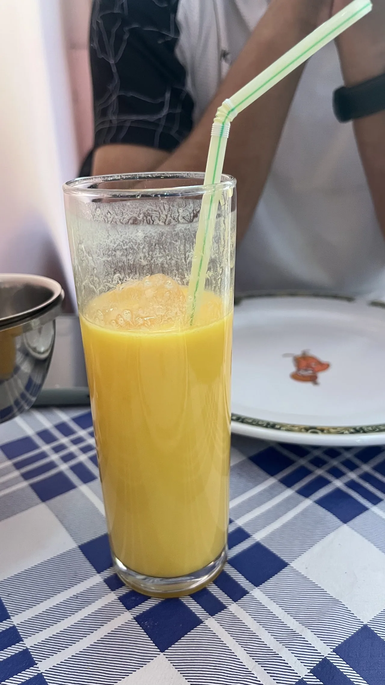 A glass of mango lassi with a straw