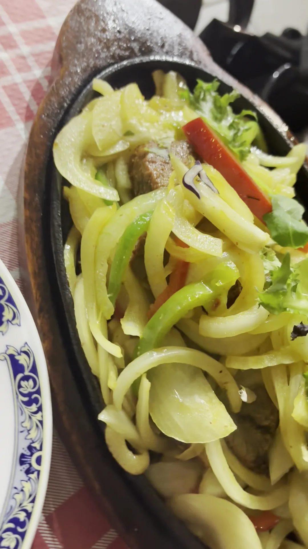 A sizzling dish of onions and peppers in a cast-iron pan