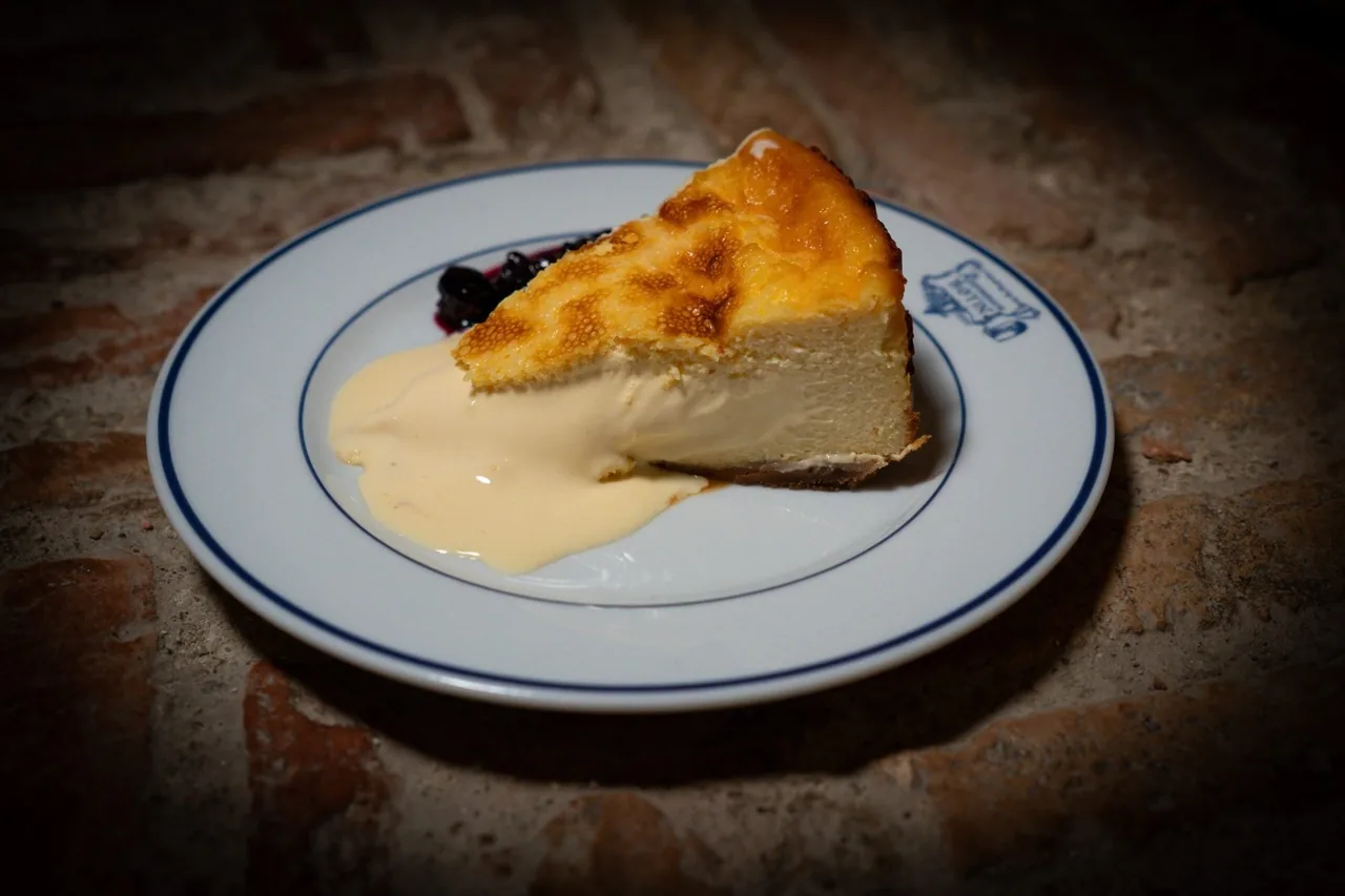 A slice of baked cheesecake with a browned top on a blue-rimmed plate