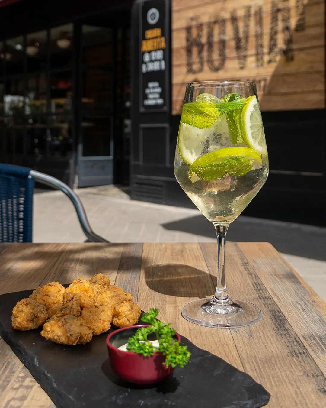 Fried croquettes with a dip beside a garnished wine spritz on a wooden table