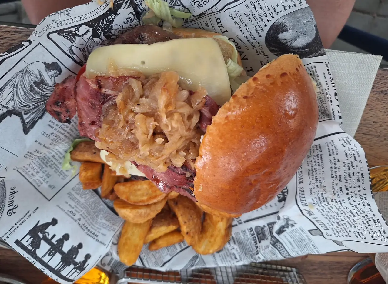 Open burger with cheese, caramelized onion and bacon beside potato wedges