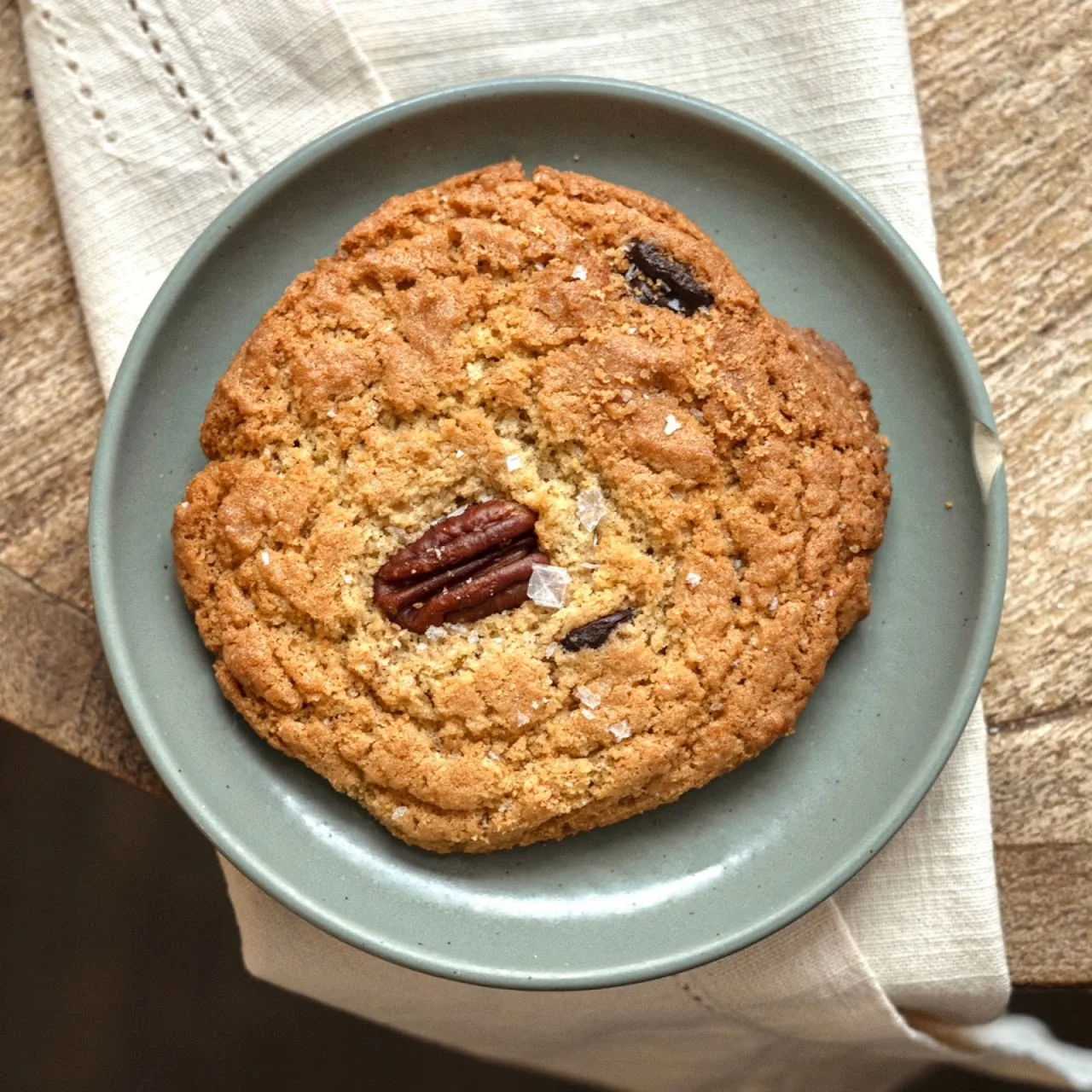 A large cookie with pecans on a plate