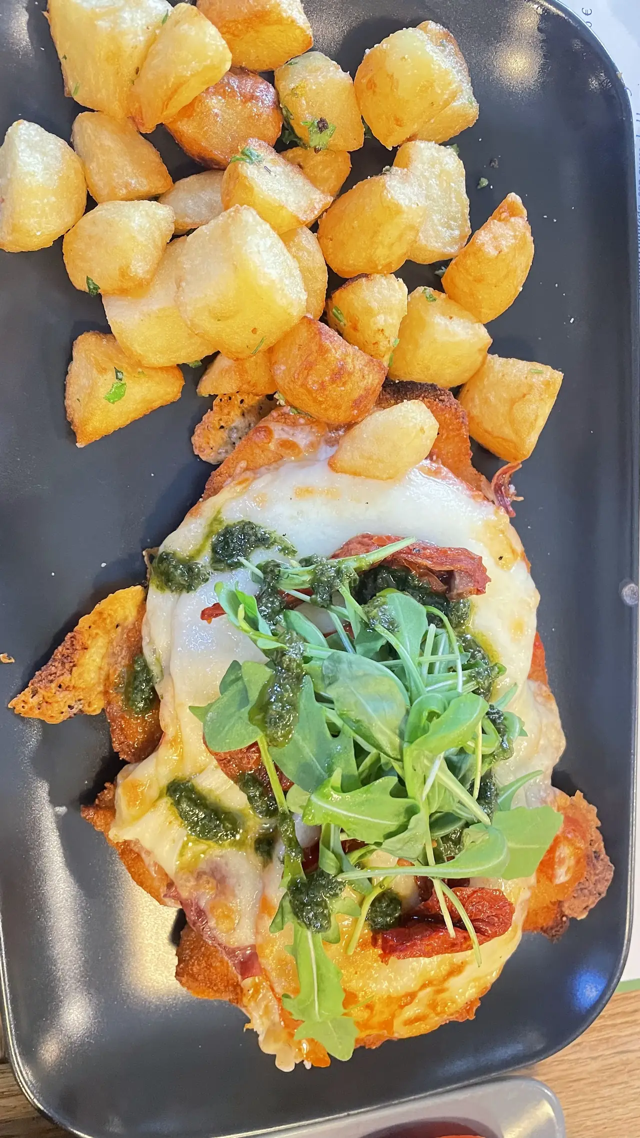 A milanesa napolitana with melted cheese and greens, served with roast potatoes