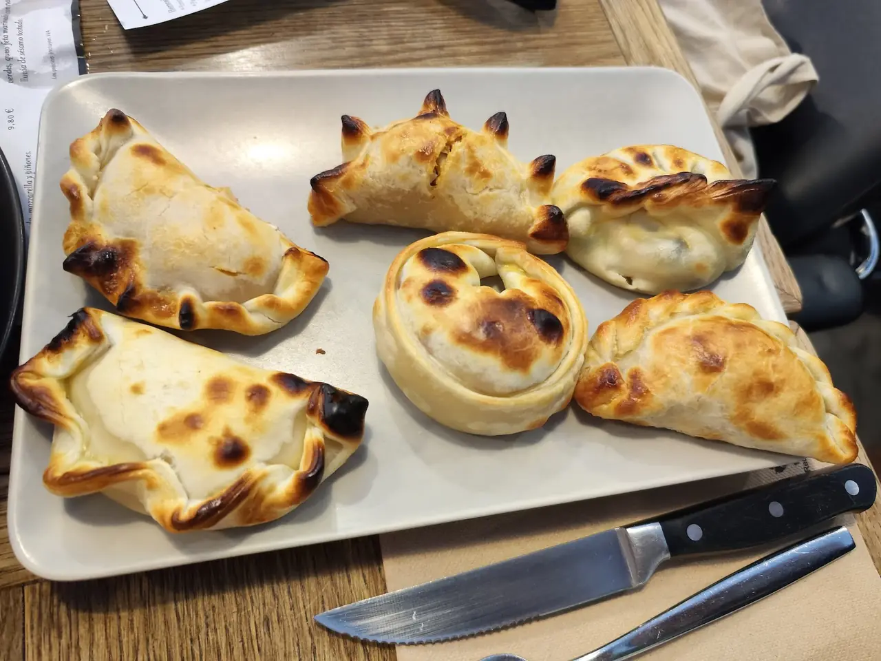 A tray of baked Argentine empanadas with a knife