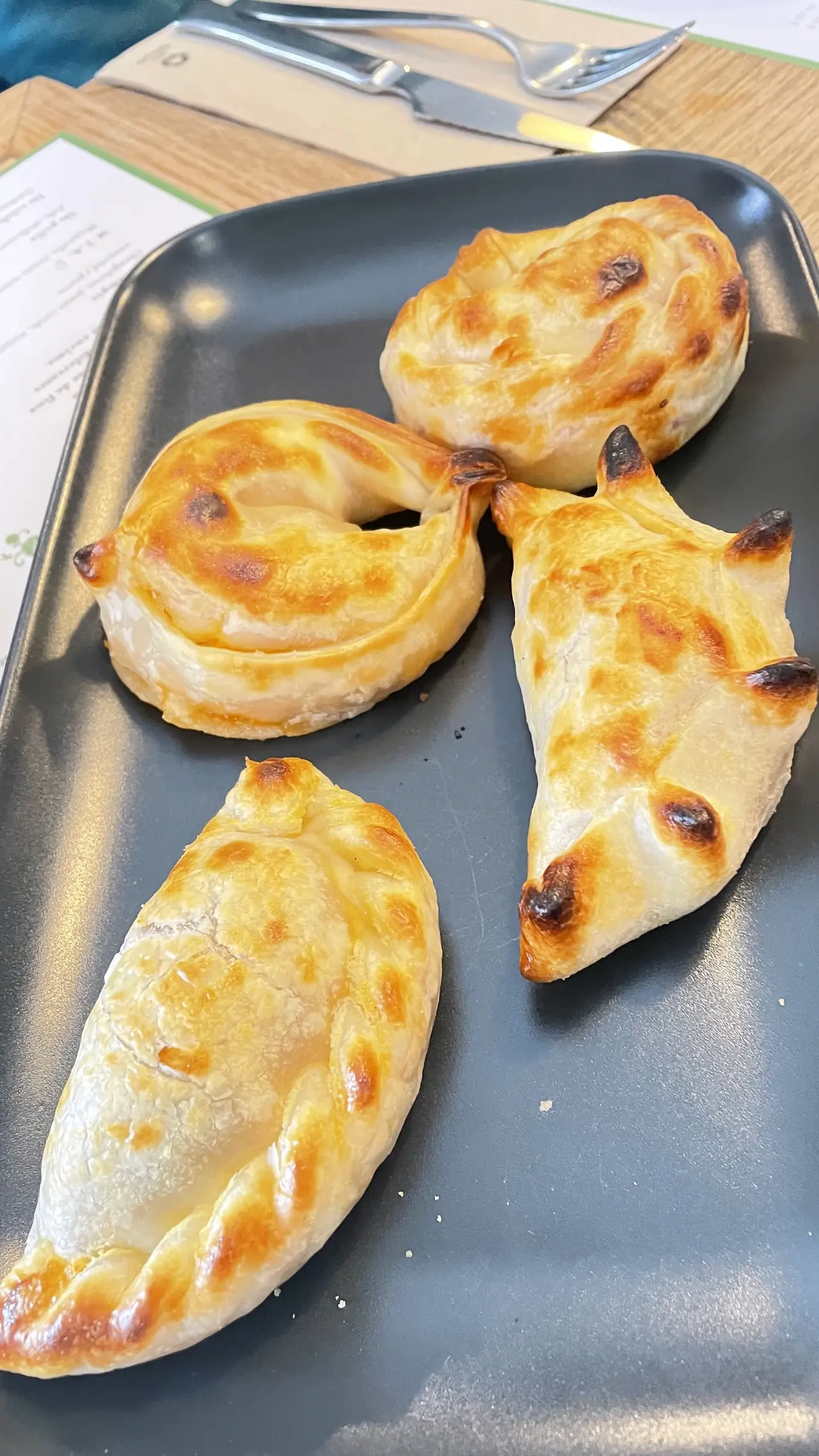 Golden baked empanadas with crimped edges on a grey plate