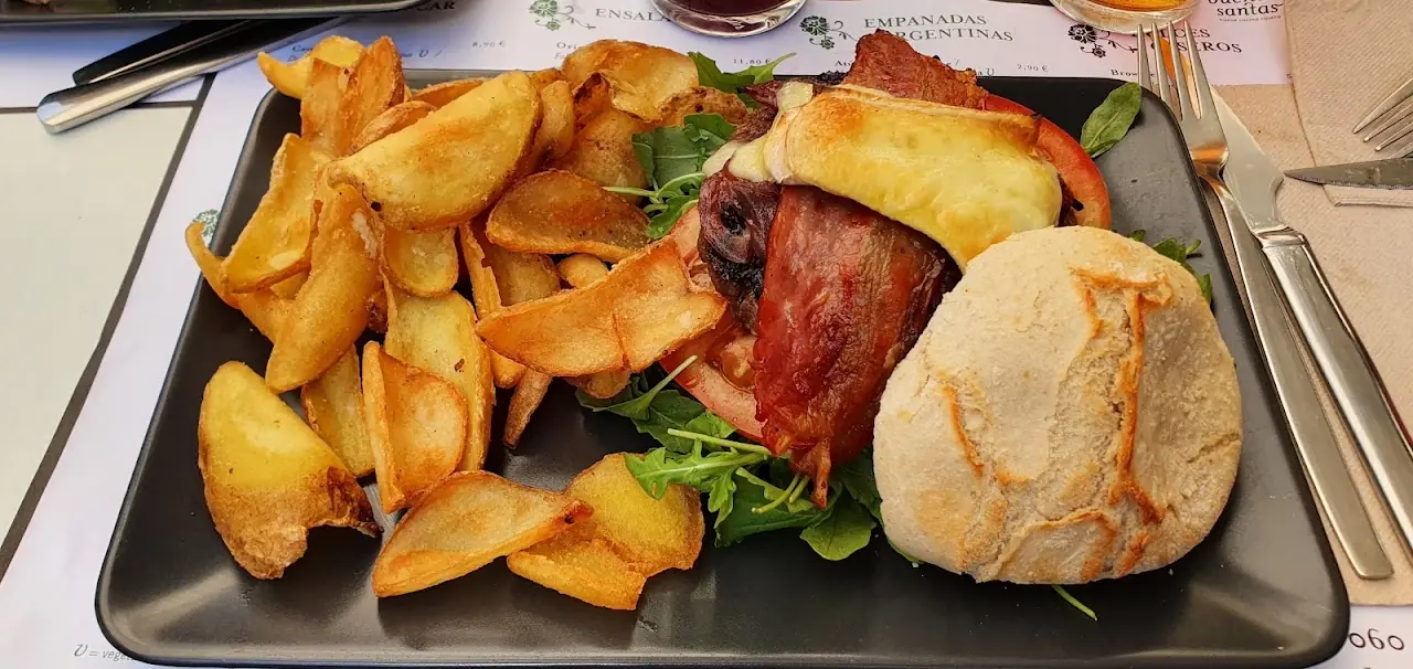 Fried potato wedges with grilled meat and a bread roll on a tray.