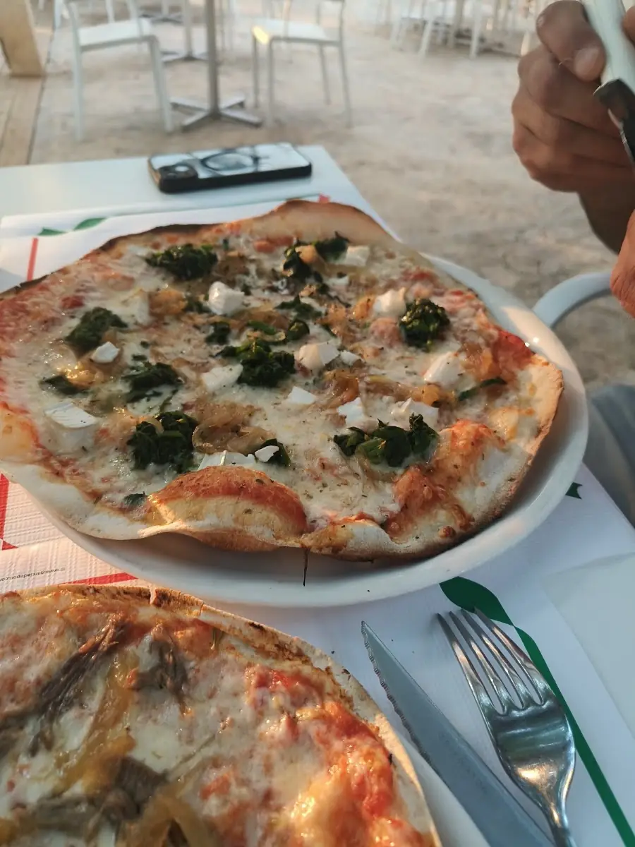 A Ca S'Arquitecte pizza with greens on a white plate