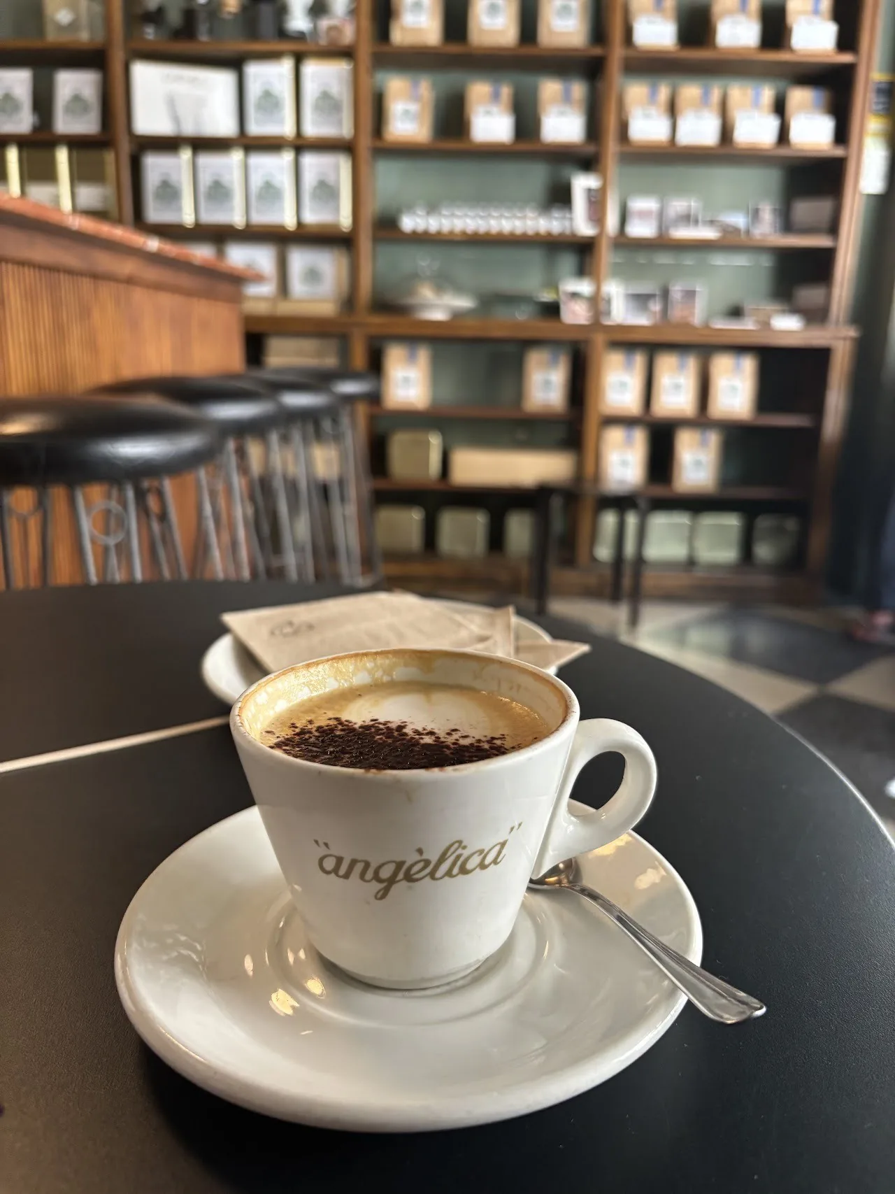 A cup of coffee on a saucer on a dark table with wooden shelves in the background