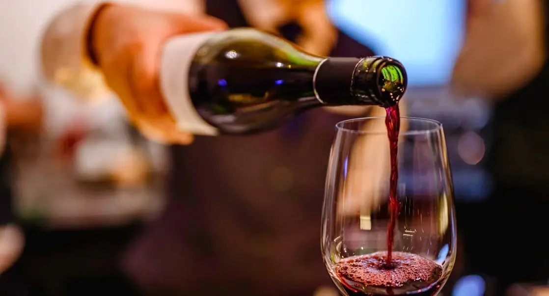 Red wine being poured from a bottle into a stemless glass