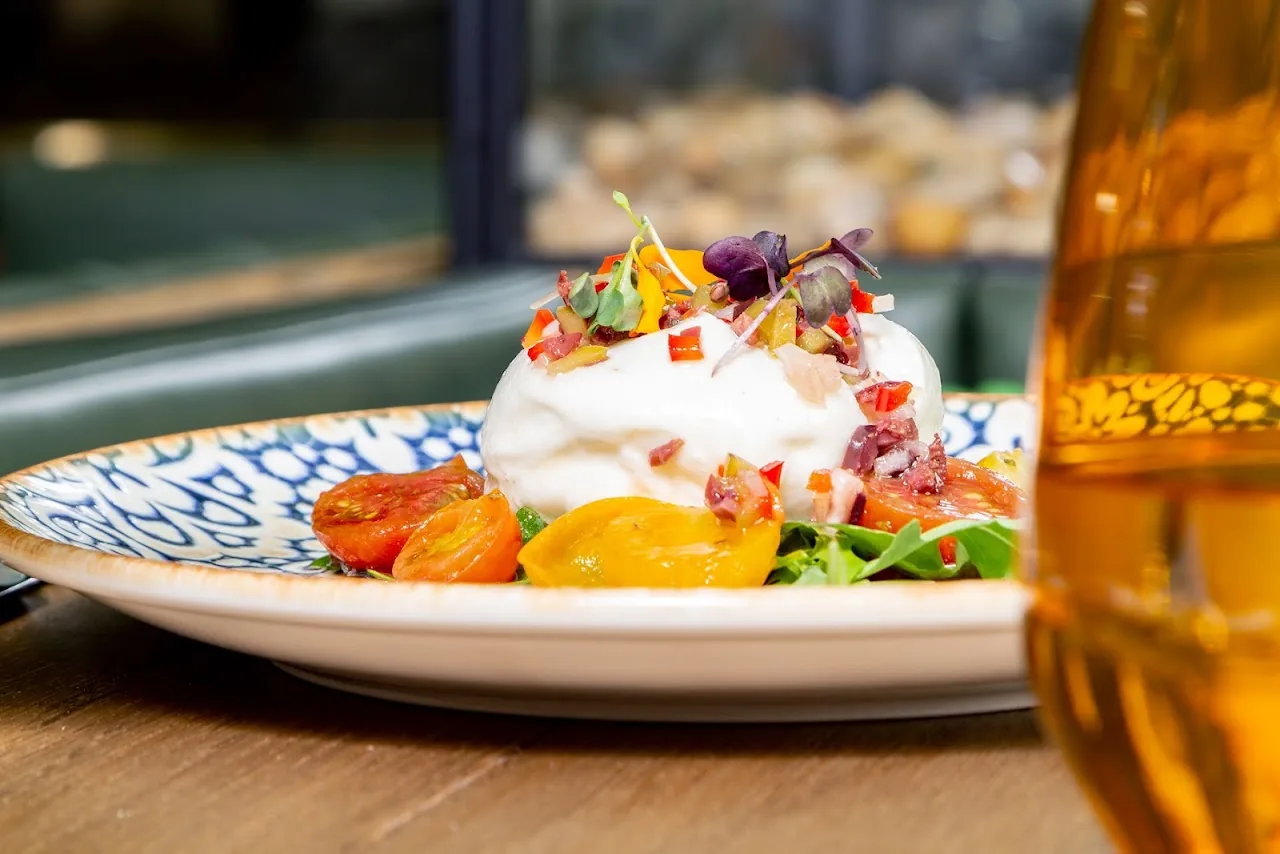 A plated dish with cream, herbs, and edible flowers
