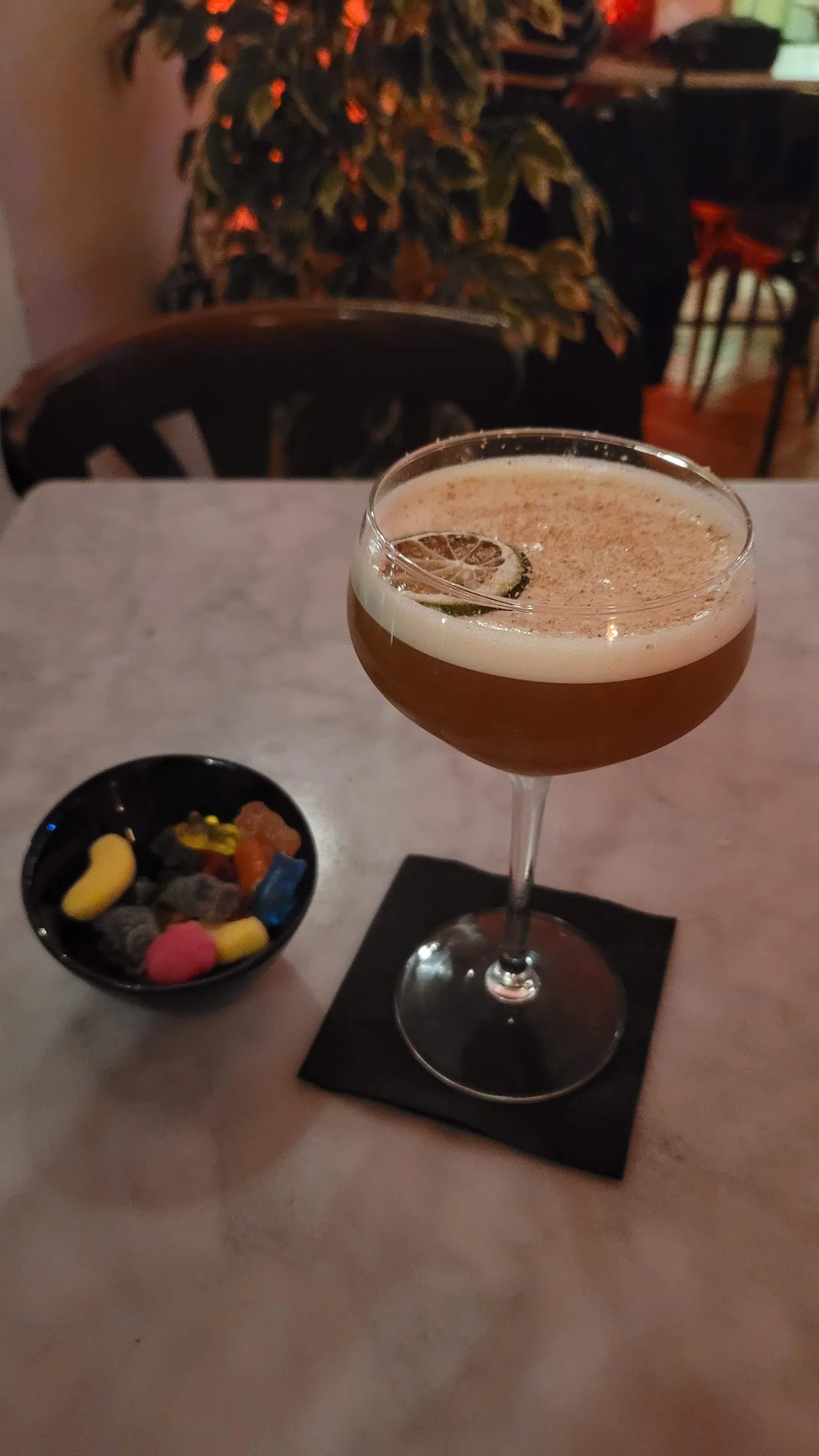A cocktail in a coupe glass garnished with a lemon twist
