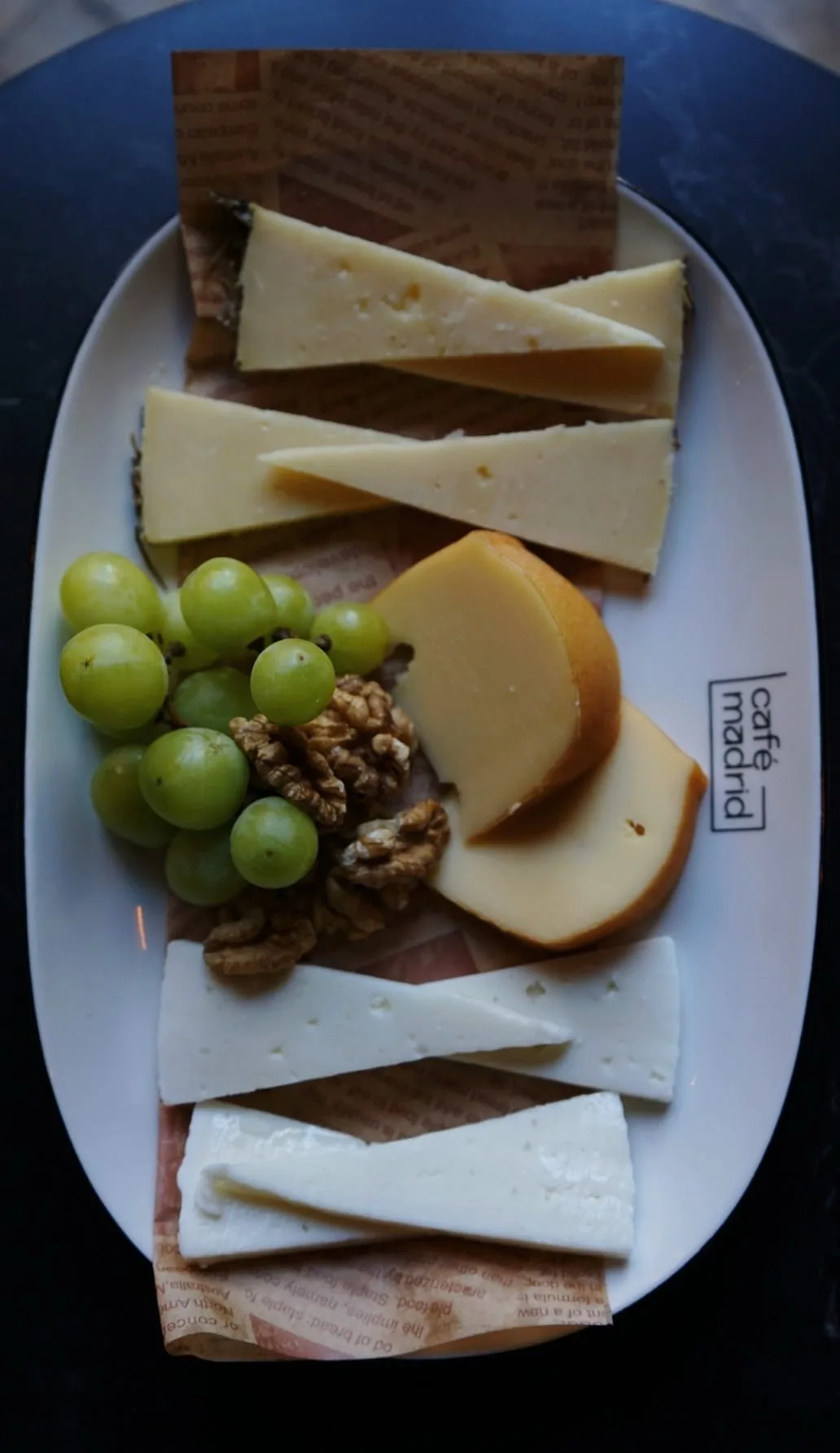 A cheese and charcuterie board with grapes and walnuts