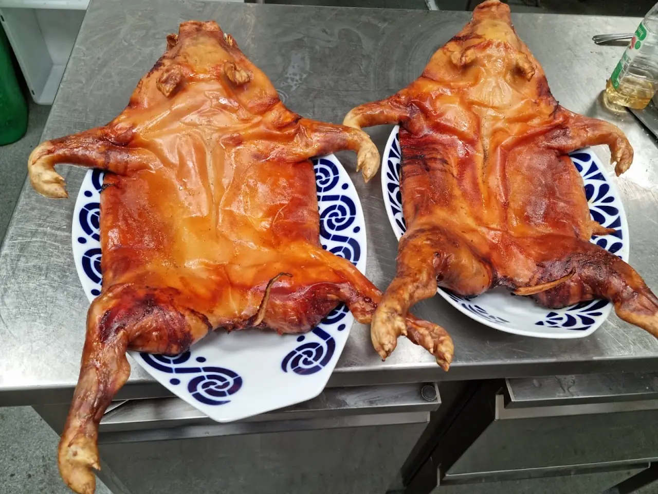 Two whole roasted suckling pigs on serving plates.