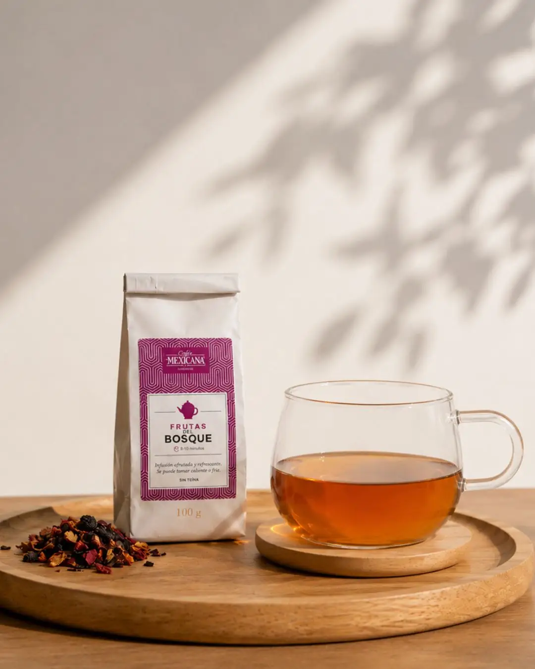 Frutas del Bosque tea bag beside a glass mug of brewed tea and loose dried fruit