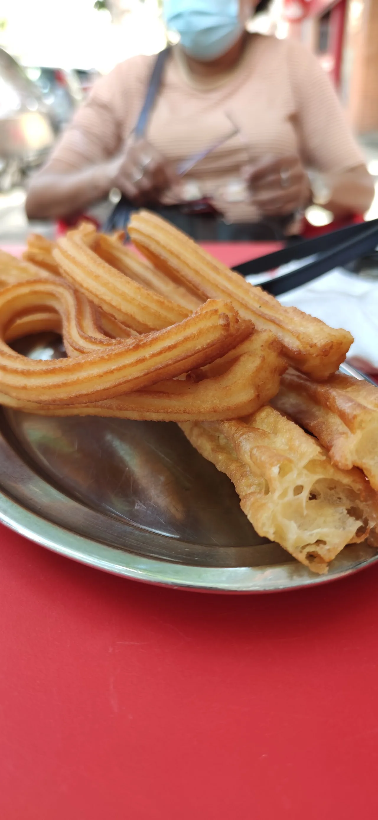 A plate of golden churros on a red table