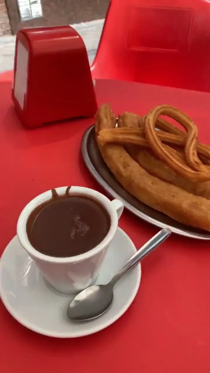 A plate of churros beside a cup of hot chocolate
