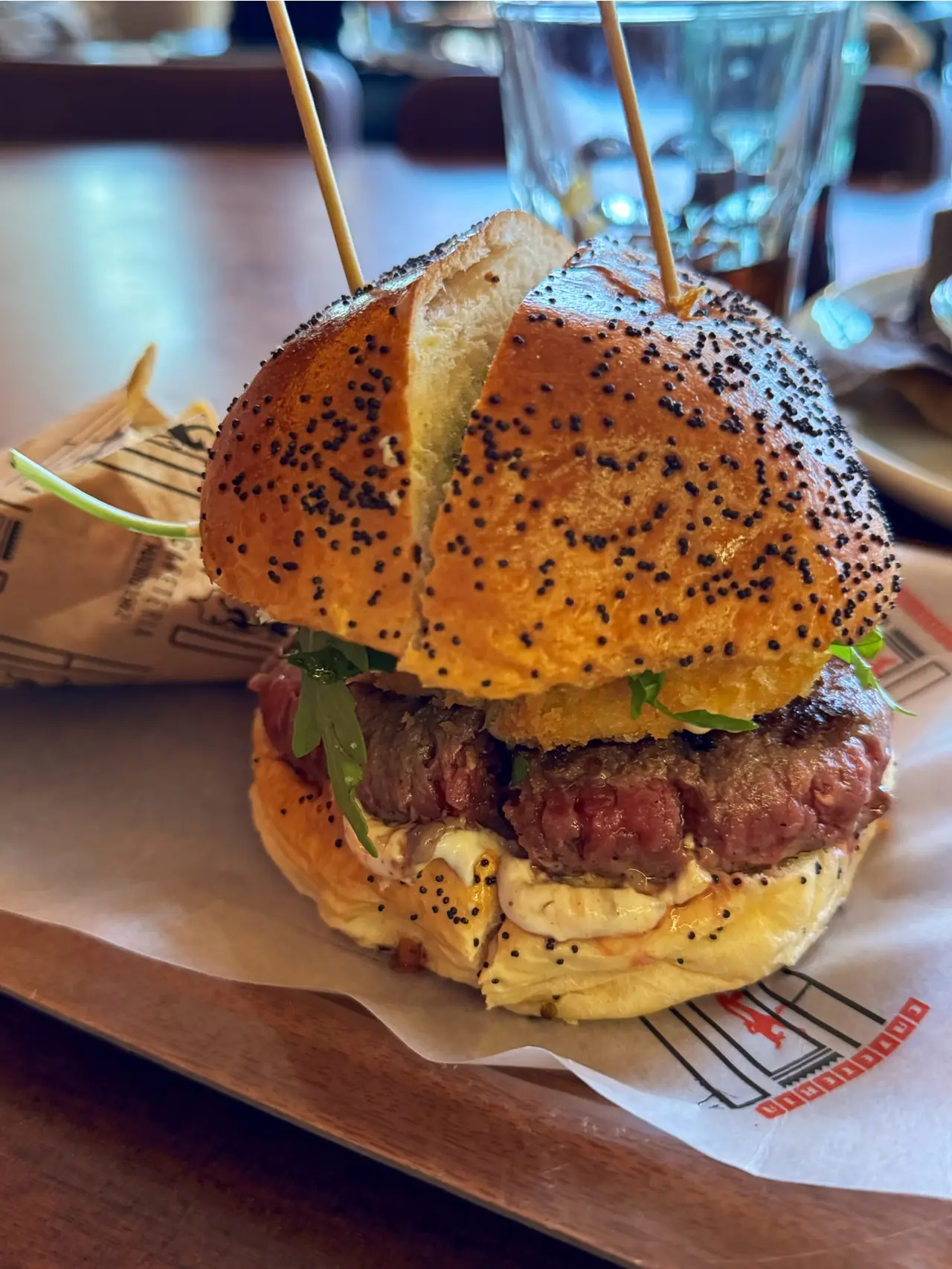 Poppy-seed bun burger with arugula and a pink-centered patty on a tray