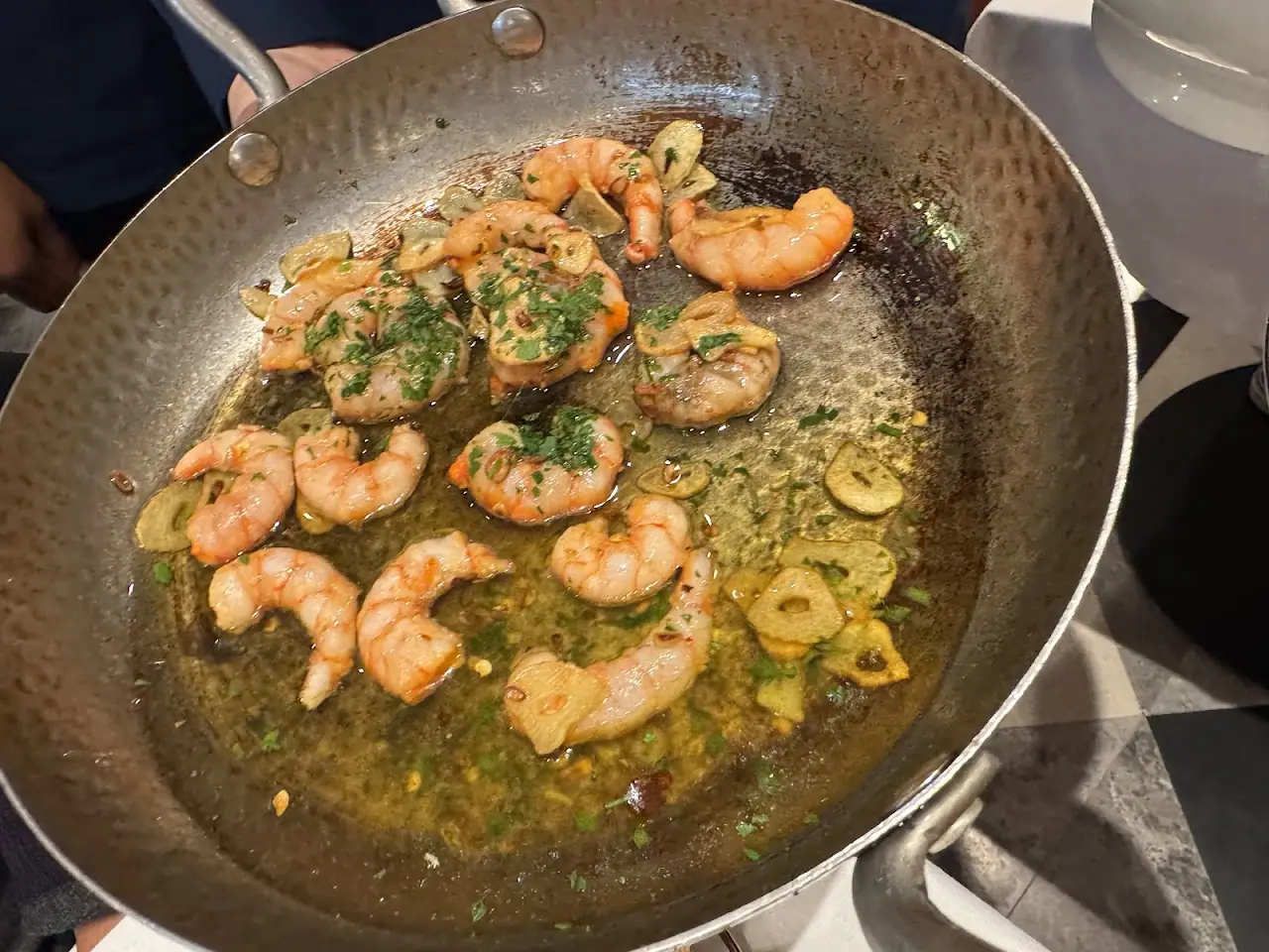 Garlic shrimp sizzling in olive oil in a metal pan