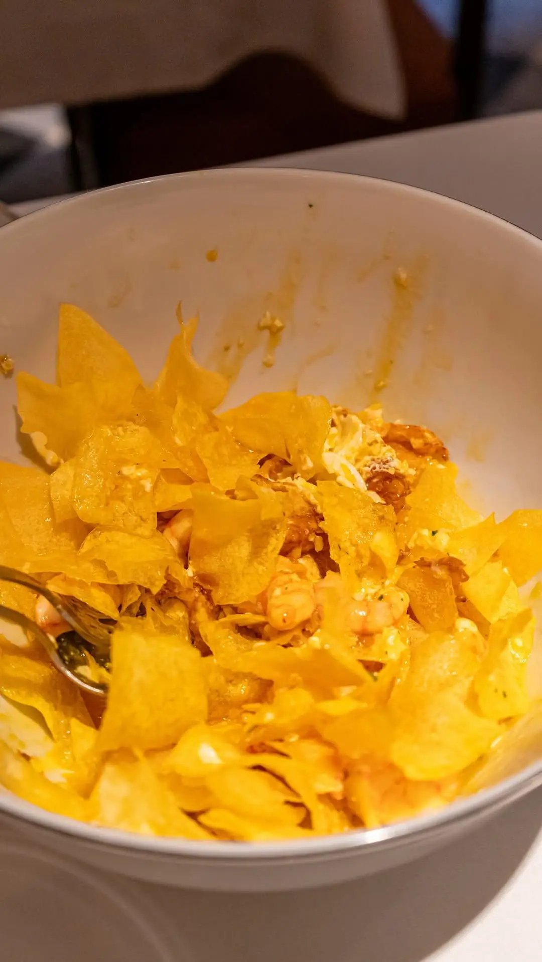 Overhead view of a bowl of crispy fried chips tossed with shrimp in a creamy sauce